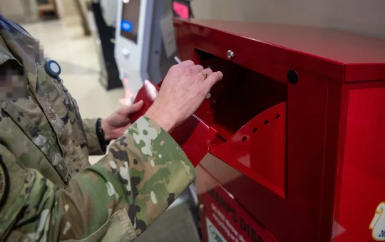 Hands drop a used item into a red sharps disposal container