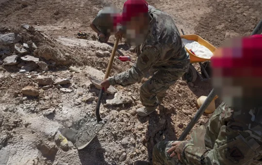 Engineers shovel stemming into a loaded borehole in rock during a blasting proficiency test