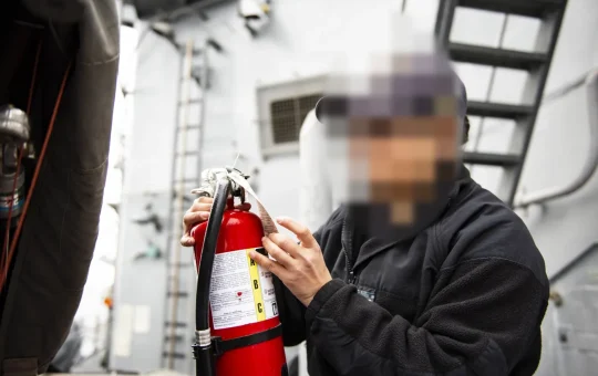 A worker checks the tag and gauge on a fire extinguisher