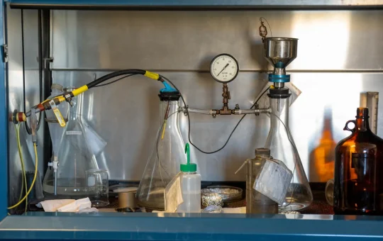 Flasks, tubing and a pressure gauge set up inside a laboratory fume hood