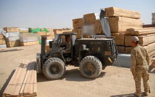 A forklift sets down banded lumber in a material yard lined with stacked lumber bundles