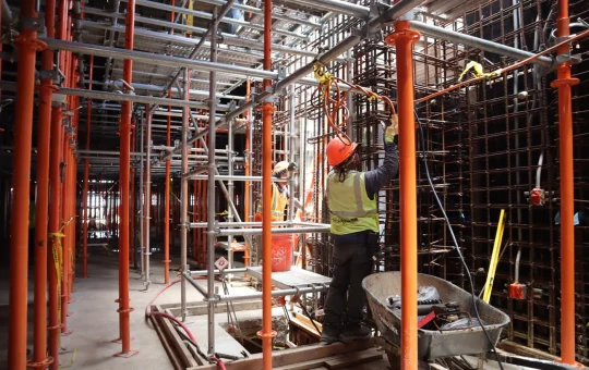 A construction worker on a scaffold platform inside a building under construction