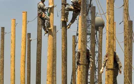 Several climbers work on utility poles in a training yard